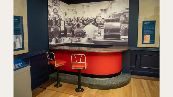 An exhibition display with red lunch counter and stools