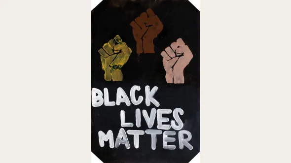 A protest sign with a black background, white text that reads Black Lives Matter, and three raised fists with varying skin tones