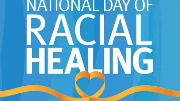 White text on a blue background reads National Day of Racial Healing. Below the words is a graphic of a yellow ribbon in the shape of a heart.