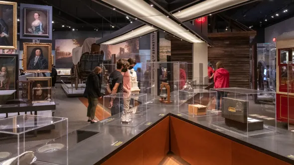 An exhibition with display cases filled with artifacts and portraits