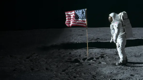 Apollo: When We Went to the Moon An astronaut in a space suit on the surface of the moon with an American flag