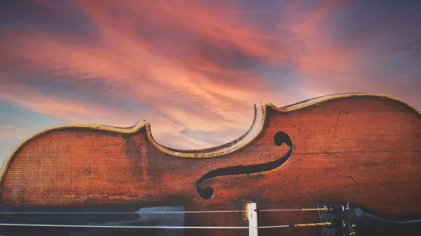 A violin on its side, with a sunset in the background.