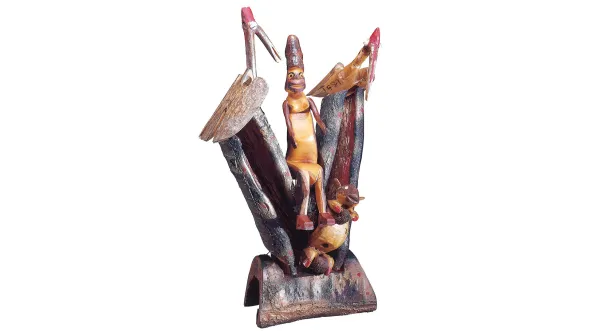 A mixed materials sculpture of a being in between two long-beaked birds with a squirrel
