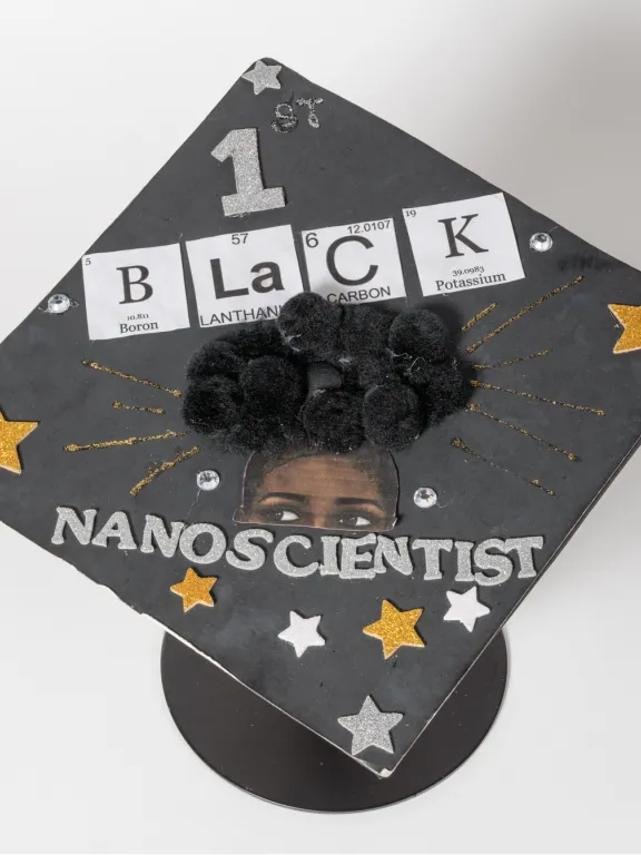 The top of a graduation cap says 1st Black Nanoscientist