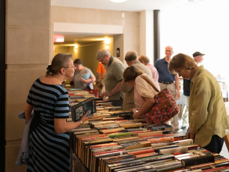 Shoppers look at used books on a table.