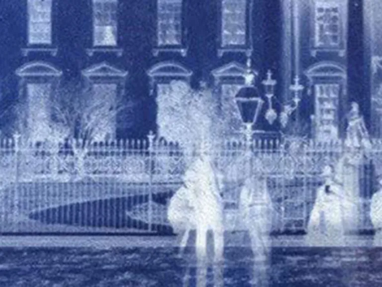 A blue and white illustration of spirits in front of a historic house