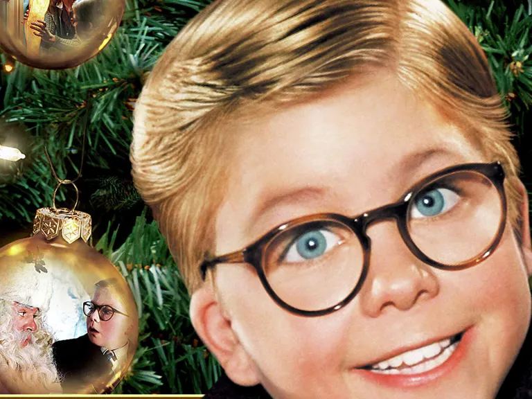 A photo of a boy in glasses in front of a Christmas tree