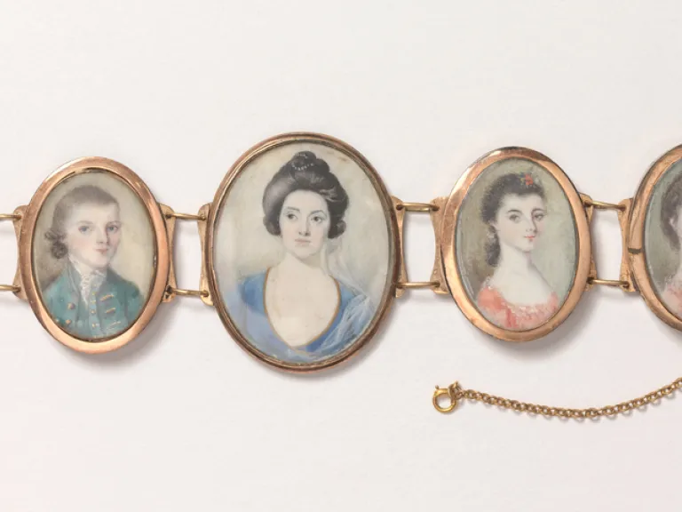 A bracelet consisting of 5 minature portraits of a woman and children framed in gold.