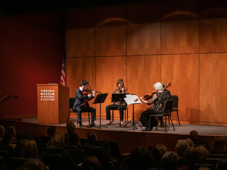 Musicians play on a stage to a packed auditorium.