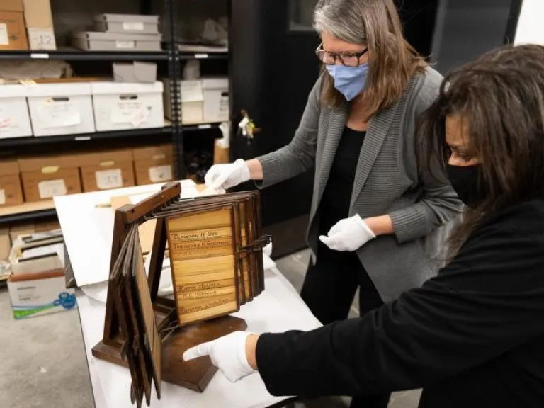 Two people look at artifacts in archival storage.