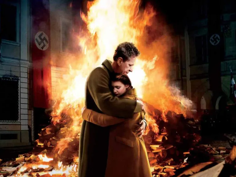 A man and a child embrace in front of a pile of burning books