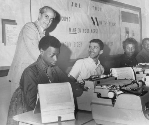 Black and white photograph of Judge Robert R. Merhige, Jr. smiling and posing with African American students 