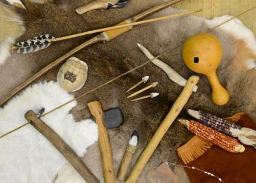 Native American tools and artifacts including corn husks, arrow heads, and feather bows