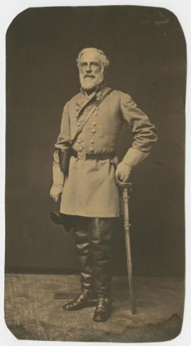 Black and white photograph of Robert E. Lee standing in a posed position holding a sword, dressed in a military uniform. 