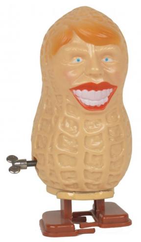 A wind-up toy in the shape of a peanut with a human face detailing red hair, blue eyes, and a smile showing teeth. 