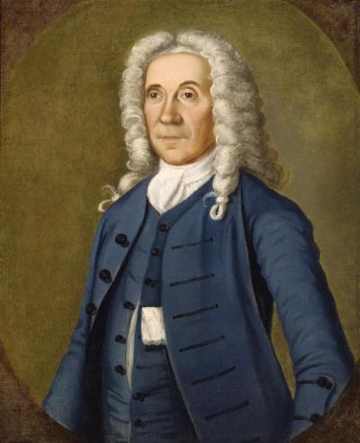 Portrait of Captain Henry Fitzhugh in a blue coat jacket, wearing a white wig and posed looking towards the left against a tan background.  