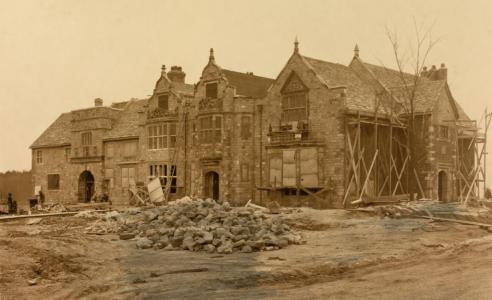  Construction of the large Virginia House showing piles of stones and material in front of the structure and portions of the house being supported by large beams.