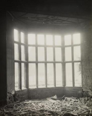 Photograph of a room with broken wood pieces and destruction on the ground in front of a large paneled window