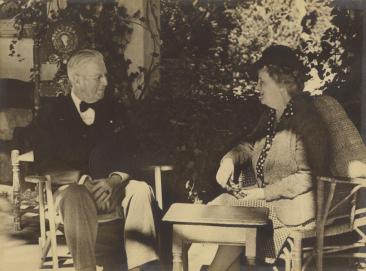 Black and white photograph of Alexander and Virginia Weddell facing each other and sitting in an outside garden area.     
